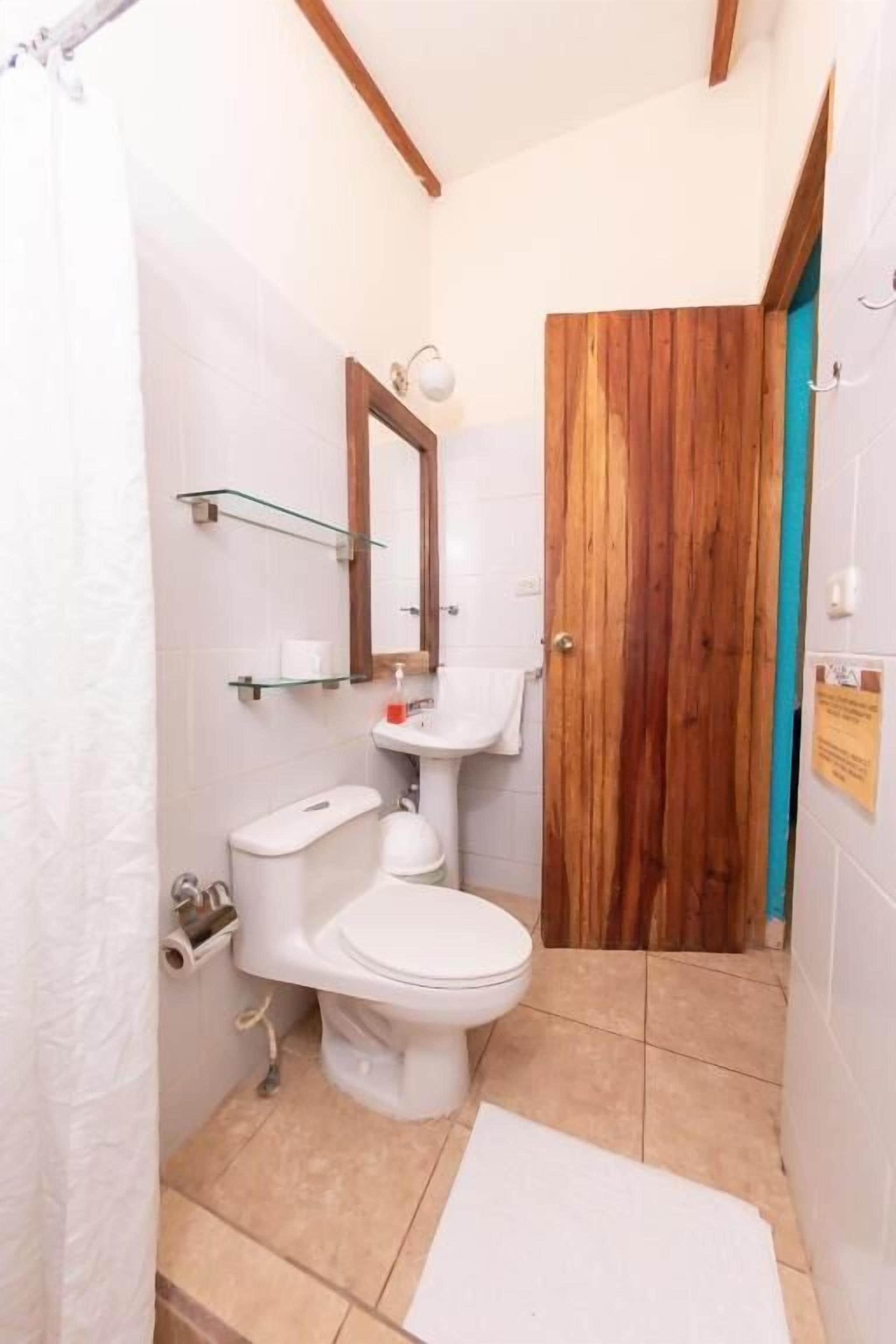 A bathroom with a toilet, sink, and mirror.