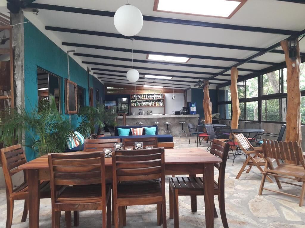 Un restaurante con mobiliario de madera, una zona de bar y ventanas amplias.