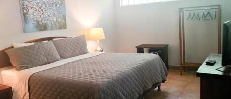 A bedroom with a bed, a nightstand, a lamp, a dresser, and a mirror.