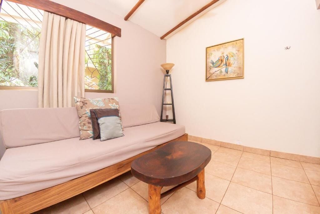 Une pièce comprenant un canapé, une petite table en bois, une lampe et un tableau accroché au mur.