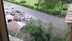 A view of a road with parked cars, a green park area, and a hill with trees. - Vacation House Dolce Angelo 21, with view of Amphitheater, in the heart of the historic center (Sutri)
