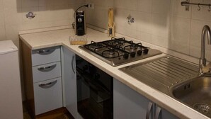 A compact kitchen with white cabinets, a gas stove, a built-in oven, and a sink. - Vacation House Dolce Angelo 21, with view of Amphitheater, in the heart of the historic center (Sutri)