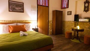 A hotel room with a bed, a wardrobe, a table with a radio, and a clock on the wall.