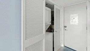 Une pièce avec une porte fermée, un placard blanc avec des portes à persiennes et une petite fenêtre.