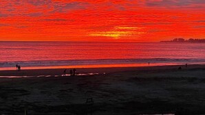 Tramonto su una spiaggia con persone che passeggiano sulla battigia.