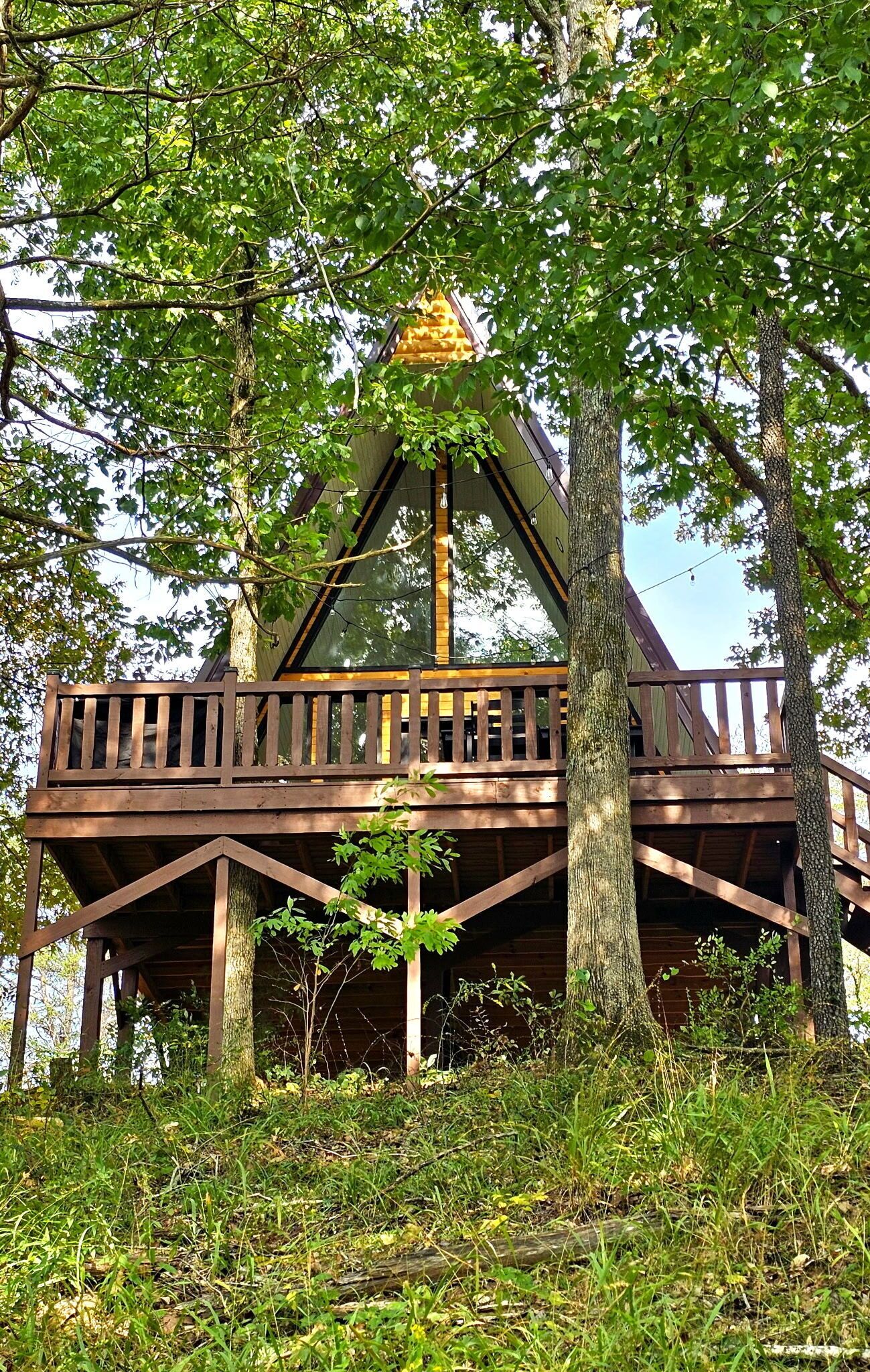 A treehouse with a wooden deck and a triangular roof structure.