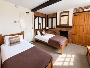 A room with two beds, a fireplace, and wooden furniture. - The George and Dragon Hotel (Sudbury)
