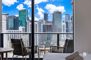Blick auf eine Stadtlandschaft aus einem Zimmer mit zwei Stühlen und einem Tisch, mit modernen Hochhäusern.