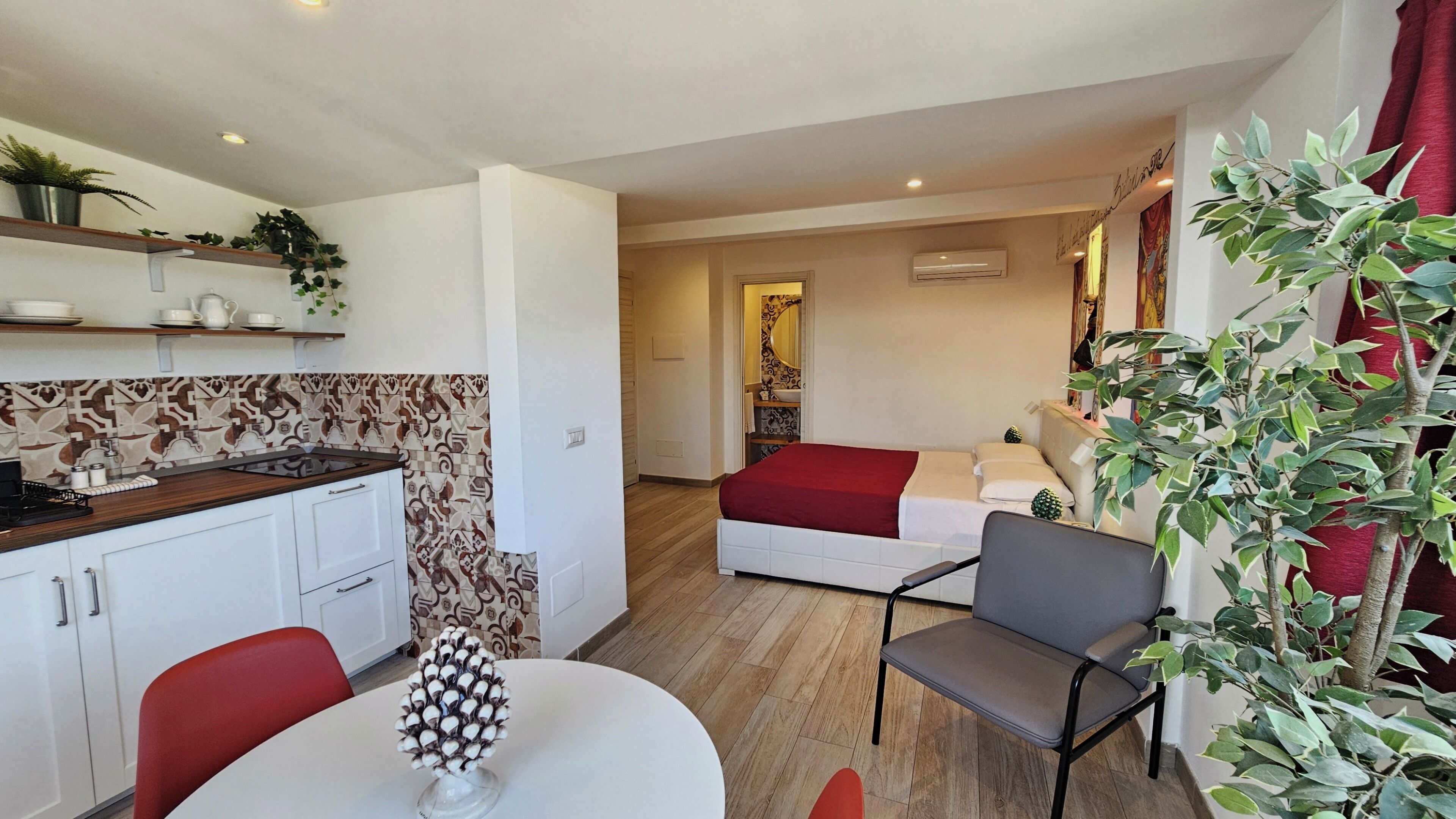 Een compacte leefruimte met een kitchenette, een eethoek, een bed en een zithoek.