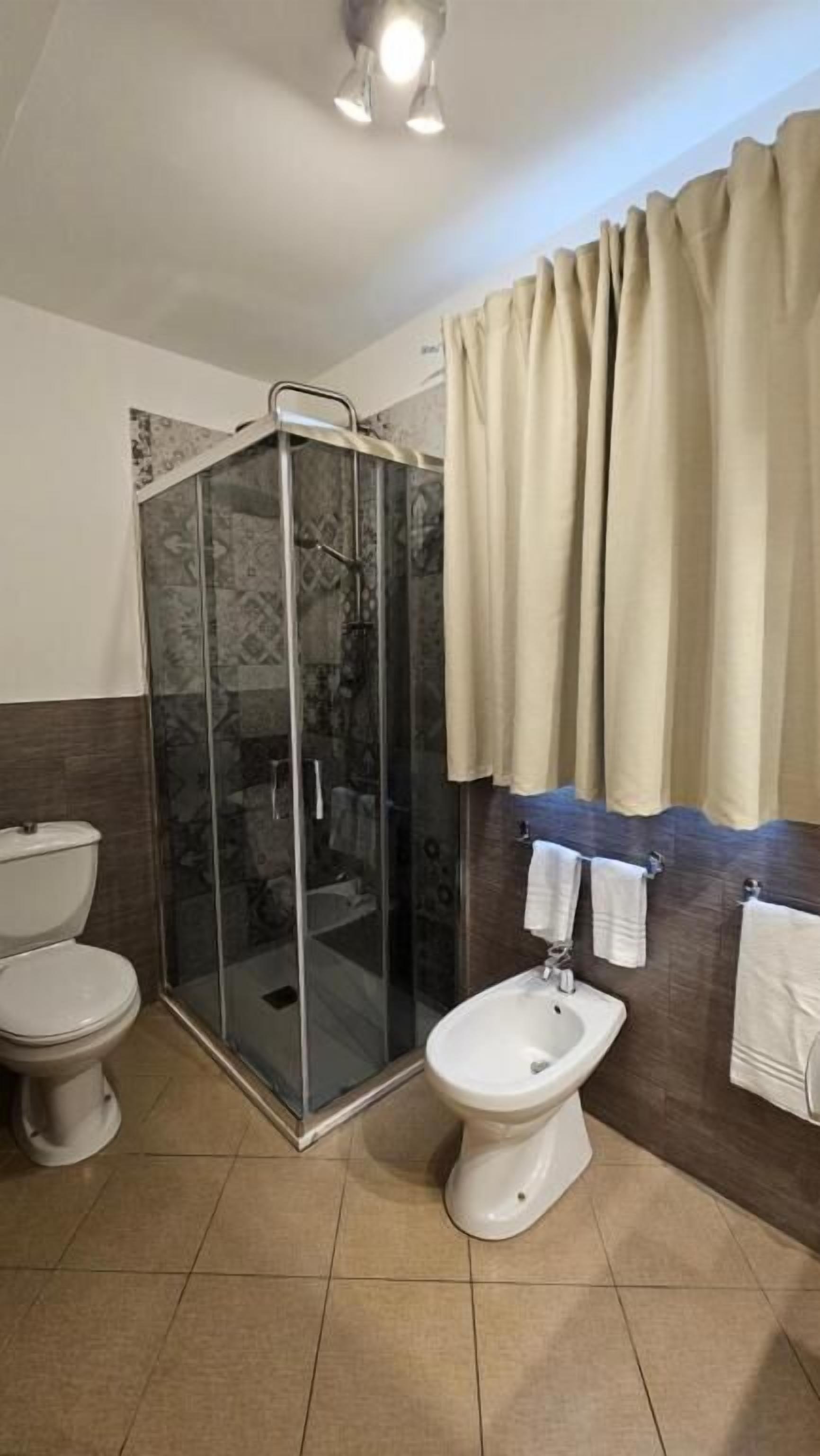 Un baño con ducha de mampara de vidrio, inodoro y bidé.