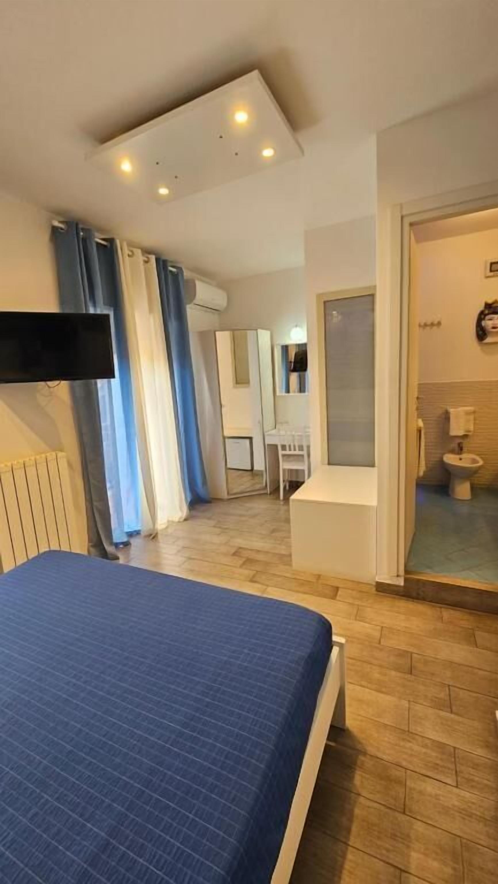 Un dormitorio con cama, televisor y baño privado con inodoro y zona de ducha.