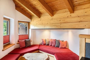 Ein gemütliches Zimmer mit Holzbalkendecke, einem roten Sofa und einem kleinen Tisch.
