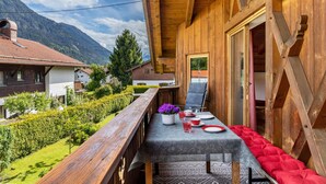A wooden balcony with a table set for two, a chair, and a view of the surrounding landscape. - Apartment 'Ferienwohnung Gipfelblick' with Mountain View, Balcony and Wi-Fi (Oberau)