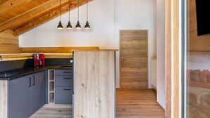 A kitchen with wooden ceiling beams, a black countertop, and a red coffee maker. - Apartment 'Ferienwohnung Gipfelblick' with Mountain View, Balcony and Wi-Fi (Oberau)