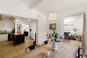 Eine moderne Küche mit Essbereich, Holzboden und Pendelleuchten.