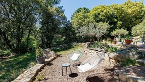 An outdoor seating area with a stone wall, a wicker chair, a small table, and potted plants. - Holiday Home 'Mer Et Montagne À Conca' with Mountain View, Private Terrace and Wi-Fi (Conca)