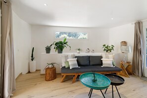 A modern living room with a sofa, a coffee table, and potted plants.