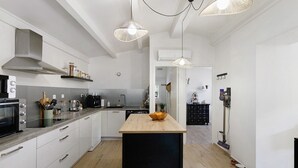 A modern kitchen with a central island, built-in appliances, and pendant lighting. - Holiday Home 'Mer Et Montagne À Conca' with Mountain View, Private Terrace and Wi-Fi (Conca)