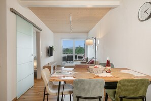 Un espace repas moderne avec une table en bois, des chaises et une horloge fixée au mur.