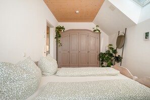 Une chambre à coucher avec un lit, une armoire, un miroir et une plante en pot.