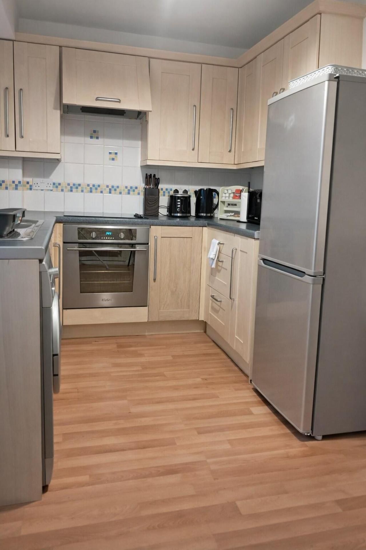 A kitchen with wooden cabinets, a stainless steel refrigerator, a built-in oven, and a coffee maker.