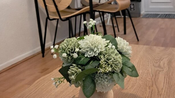 A dining area with a round wooden table, two chairs, and a vase with flowers. - 2 Bed Home - Parking for 2, Wifi & Garden (Nottingham)