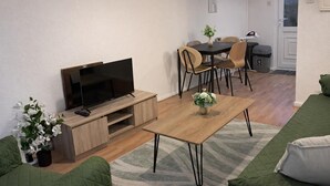 A living room with a TV, a dining table, chairs, a sofa, and a small plant. - 2 Bed Home - Parking for 2, Wifi & Garden (Nottingham)