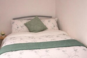 A bed with a floral-patterned bedspread, a green knitted throw, and a single green pillow. - 2 Bed Home - Parking for 2, Wifi & Garden (Nottingham)