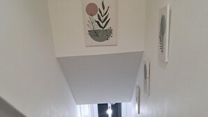 A staircase leading to a door with a doormat, white walls, and a ceiling light. - 2 Bed Home - Parking for 2, Wifi & Garden (Nottingham)