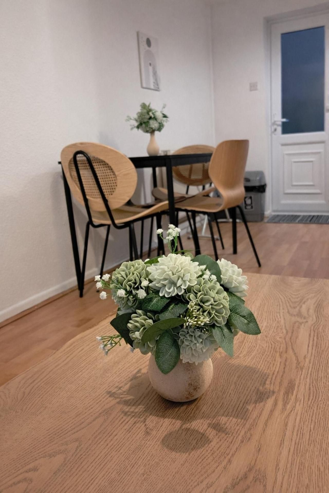 Un comedor con una mesa, sillas y un florero con flores.