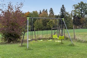 A swing set in a grassy field with trees in the background. - Wiesenblick Apartment with Shared Terrace, Garden View, and Wi-Fi (Deggenhausertal)