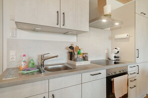 A modern kitchen with stainless steel appliances, a built-in oven, and a sink. - Wiesenblick Apartment with Shared Terrace, Garden View, and Wi-Fi (Deggenhausertal)