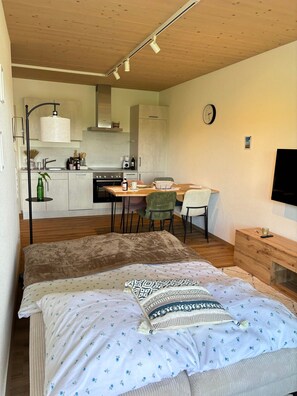 Ein modernes Schlafzimmer mit einem Bett, Nachttischen und Blick zur Küche.