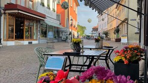 A cobblestone street with outdoor seating, a flower display, and buildings with signage. - Panoramic View Holiday Apartment (Deggenhausertal)