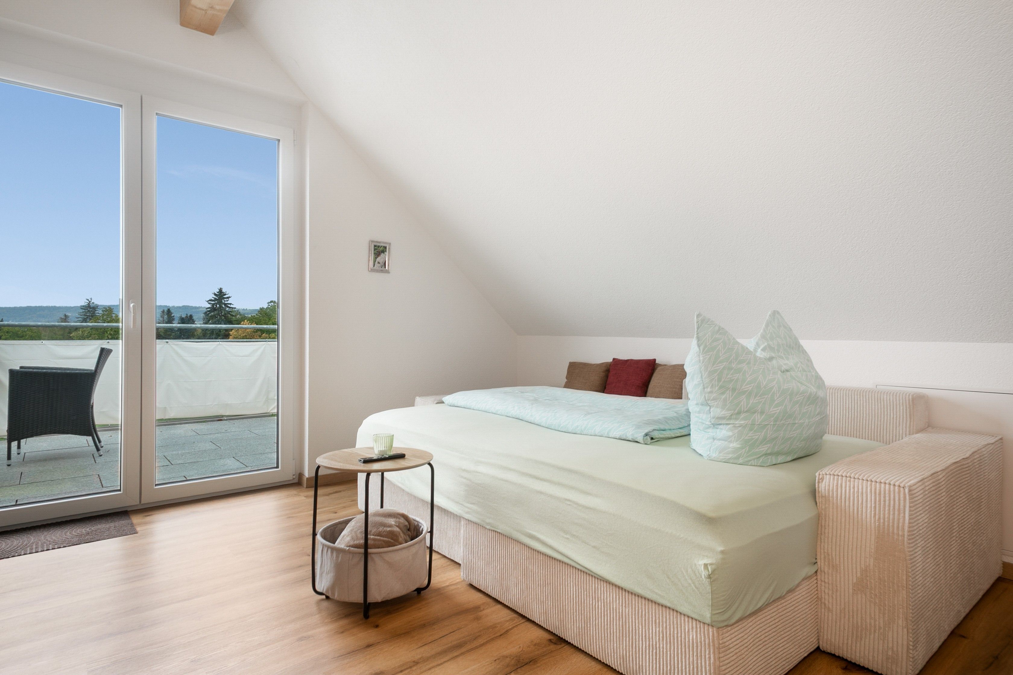 A bedroom with a bed, bedside table, and a view through a sliding glass door.