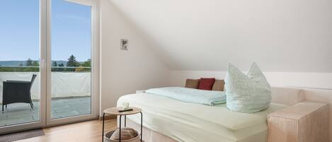 A bedroom with a bed, bedside table, and a view through a sliding glass door.