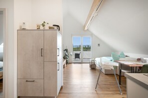 Une chambre moderne dotée d’une grande armoire, d’un coin repas avec une table et des chaises, et offrant une vue sur l’extérieur grâce à une porte coulissante.