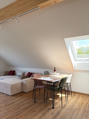 Ein Loft-Zimmer mit Esstisch, Stühlen, einer Couch und einem Fenster mit Blick.