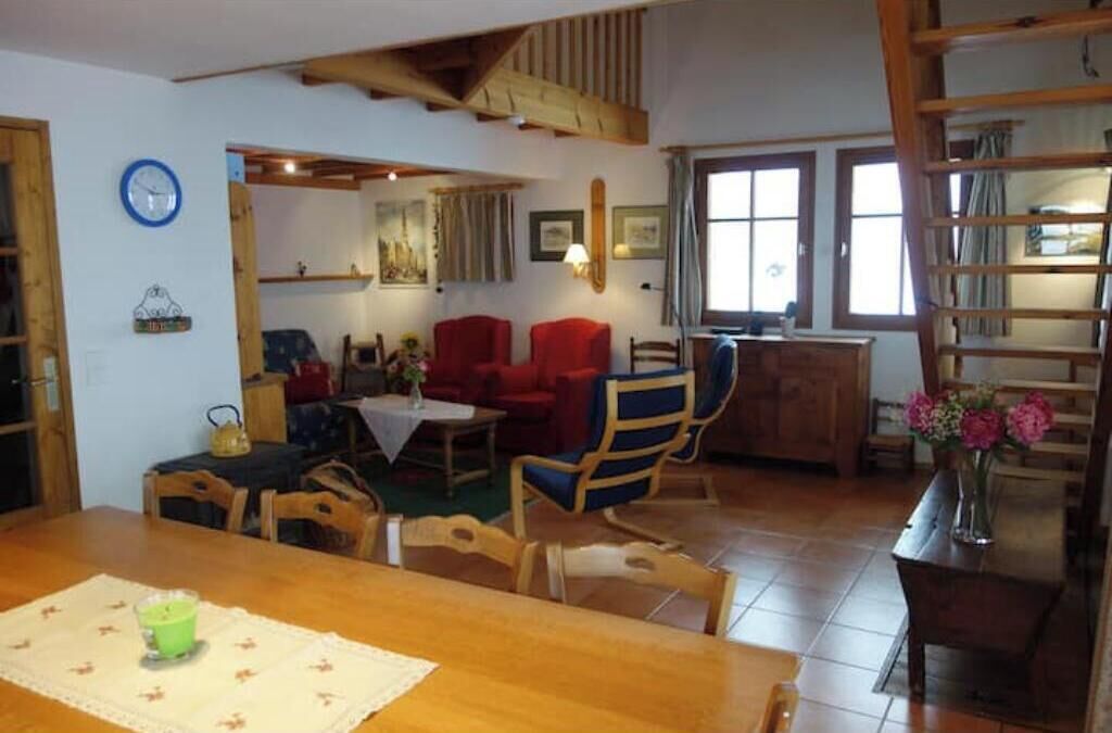 Un coin repas avec une table en bois, des chaises et une horloge au mur.