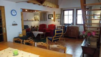 Un coin repas avec une table en bois, des chaises et une horloge au mur.