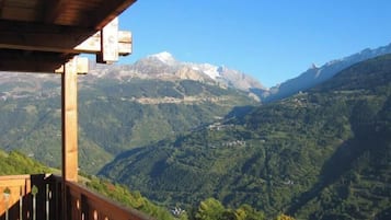 Un balcon en bois offrant une vue sur un paysage montagneux.