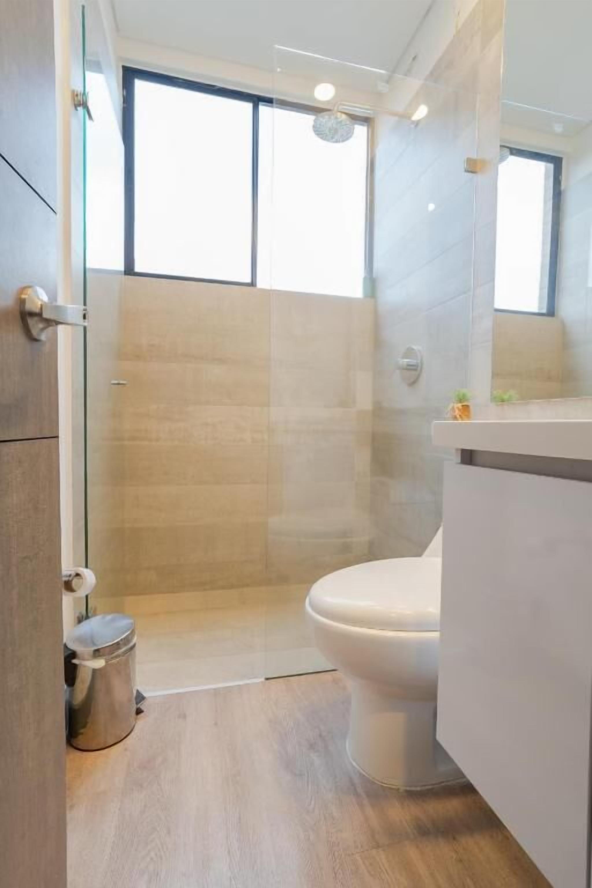 A modern bathroom with a shower, toilet, and vanity.