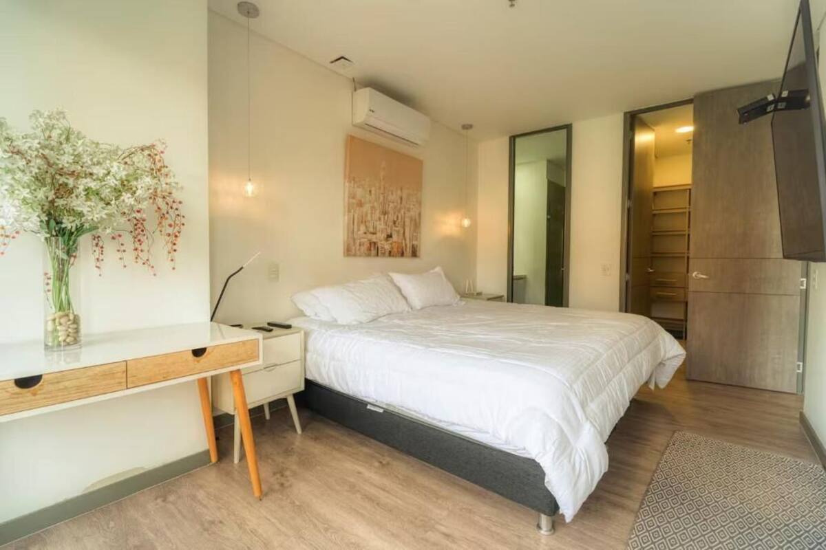 A modern bedroom with a bed, bedside table, and a desk.