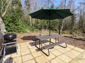 A patio with a grill, a table, and an umbrella. - Gardeners Lodge (Belford)