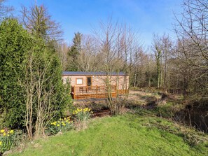 A cabin with a wooden deck, surrounded by trees and a grassy area. - Gardeners Lodge (Belford)