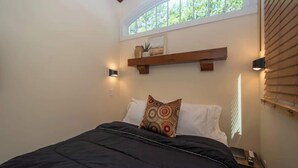 A bedroom with a bed, a window, a shelf, and a nightstand. - Saddle (Anderson)