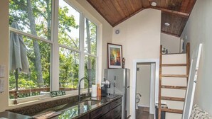 A kitchen with large windows, a wooden ceiling, and a view of trees. - Saddle (Anderson)