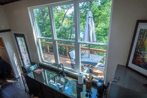 Eine Küche mit großem Fenster, einer Terrasse und Blick auf Bäume.