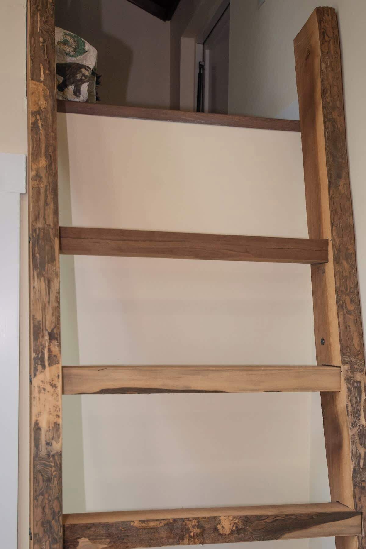 Een houten ladder met drie treden tegen een muur.