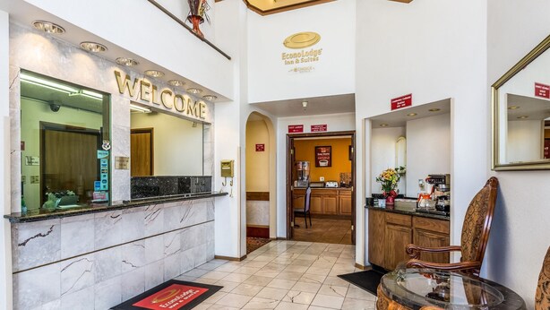 A hotel reception area with a marble counter, a 'WELCOME' sign, a guest laundry sign, and a coffee machine. - Econo Lodge Inn and Suites Albuquerque East I-40 Eubank Exit (Albuquerque)